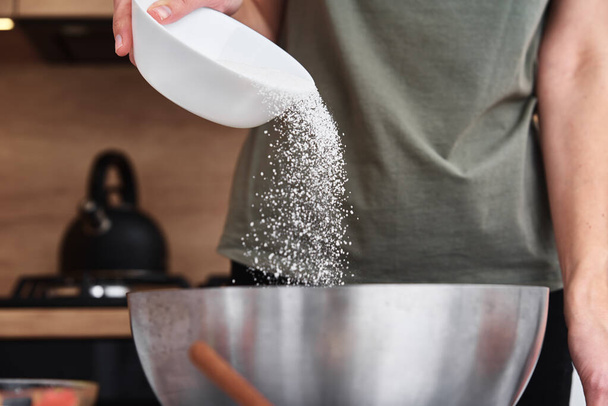Woman in the kitchen cooking a dough. Hands pour flour into a bowl - Фото, изображение
