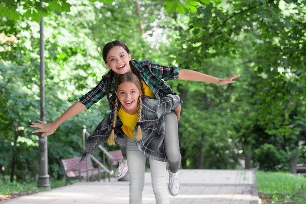 Happy childhood friends have fun piggybacking in park on summer day, holidays - Фото, зображення