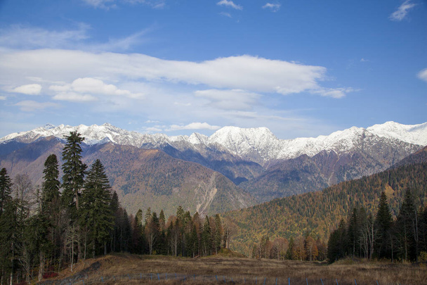 クラスナヤ・ポリアナ、ソチ、北コーカサスの山々、秋の木々を背景に雪に覆われた山, - 写真・画像