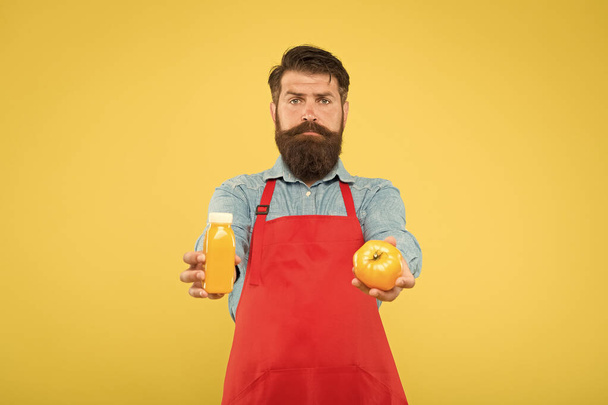 Fresh juice. Squeezing smoothie. Delivering fresh vitamins. Hipster smoothie beverage. Man bearded chef hold organic natural tomato and bottle yellow background. Vegetarian nutrition. Smoothie drink - 写真・画像