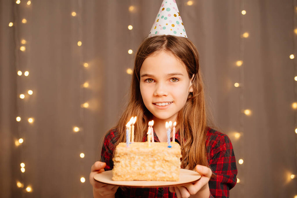 Gelukkig tienermeisje met verjaardagstaart. traditie om wensen te maken en vuur uit te blazen - Foto, afbeelding