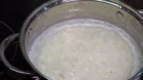 Le riz est cuit dans une casserole. Cuisson du porridge pour le petit déjeuner. Accompagnement pour les plats principaux, déjeuner. Gros plan sur l'eau bouillante et les grains bouillis. - Séquence, vidéo