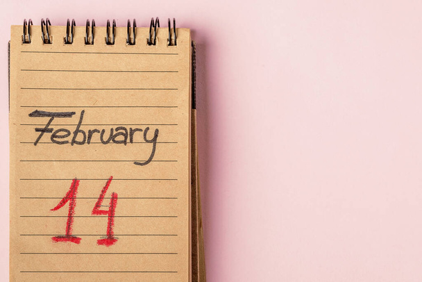 14 февраля написано в переработанной бумажной записной книжке на розовом фоне. Концепция Дня Святого Валентина. Копирование текста - Фото, изображение
