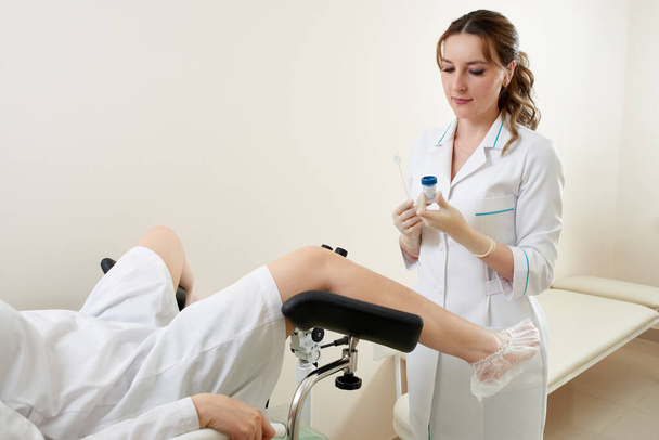 Gynaecologist examining a patient sitting on gynecological chair - Foto, imagen