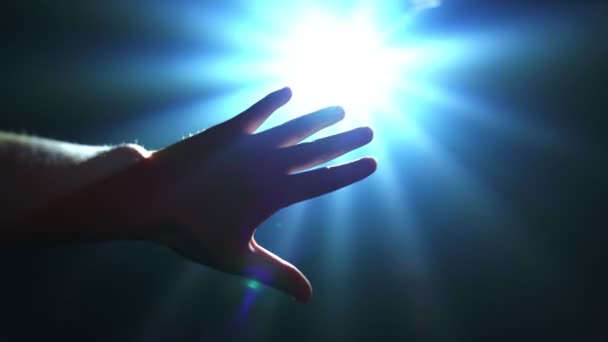 Ruka natahuje ruku, aby zakryla zářící bodové světlo - Záběry, video