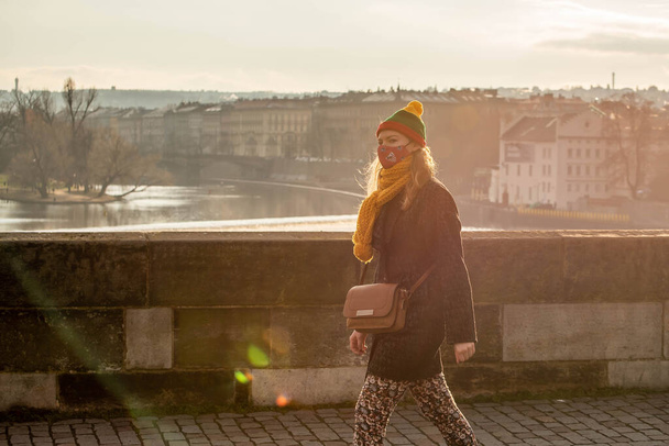 Praga, República Checa. 01-09-2021. Mulher com máscara andando na Ponte Charles, em um pôr do sol no inverno em Praga. - Foto, Imagem