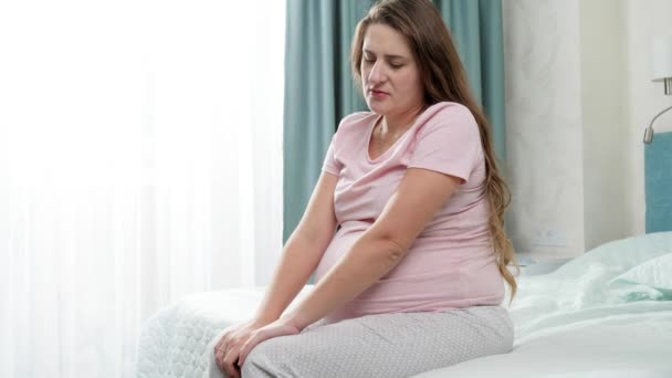 Szomorú terhes nő ül és remeg az ágyon. Az anyai és terhességi depresszió fogalma. - Felvétel, videó