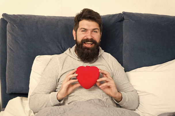 mature man in bed with gift. brutal man relaxing in bedroom on holiday. valentines day surprise. love and romance. being romantic is nice. to my beloved valentine. holiday shopping online - Foto, Imagen