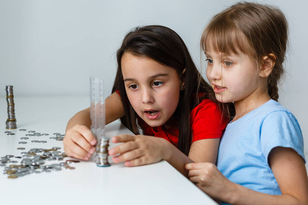 Двоє дітей рахують монети разом
 - Фото, зображення
