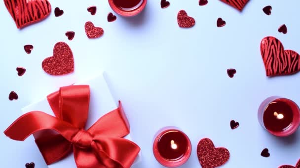 Saint Valentin minimal : coeurs d'amour rouges, boîte cadeau romantique, bougie sur fond blanc. Sainte Valentin, fête des mères, cartes de vœux d'anniversaire, invitation, concept de fête - Séquence, vidéo