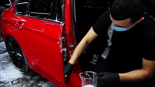 Az ember mossa nehezen elérhető helyeken autó ajtók ecsettel - Felvétel, videó