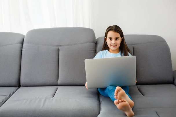 Cute little girl using laptop at home. Education, online study, home studying, distance learning, schoolgirl children lifestyle concept - Photo, Image