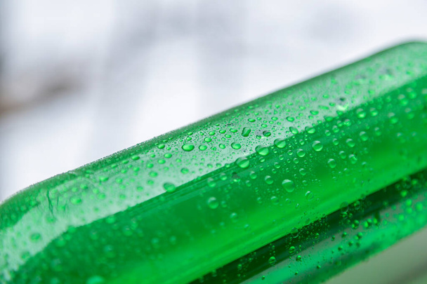 Part of bright green plastic bottle on blurred light background - Photo, Image