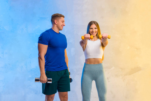 Attractive young couple in sport wear doing exercise in the gym. Strength and motivation concept. Workout online theme - Photo, Image