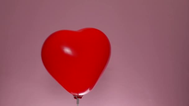 Balão em forma de coração girar sobre fundo rosa. Conceito do Dia de São Valentim - Filmagem, Vídeo