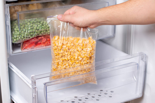 Frozen corn in bag in freezer, close up. Frozen food - Fotoğraf, Görsel