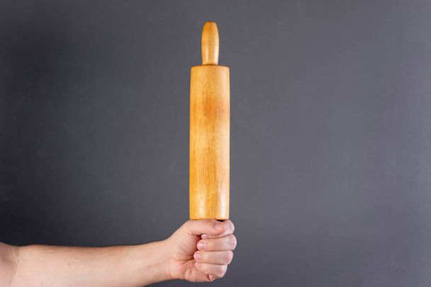 Rolling pin in male hand on gray background - Foto, afbeelding