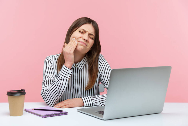 Unhappy dissatisfied woman office worker touching cheek feeling pain and discomfort in oral cavity, toothache and gums inflammation. Indoor studio shot isolated on pink background - Foto, immagini