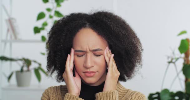 Portrét afro-americké kudrnaté vlasy smutná unavená žena pocit bolesti hlavy horečka trpí migrénou symptom překonává stres drží ruce za hlavou myšlení nad myšlenkou plán připomíná informace - Záběry, video