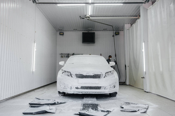 Modern washing with foam and high-pressure water of a white car. Car wash - Фото, зображення