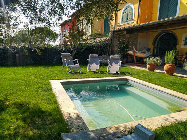 Pool mit Liegestühlen im Garten an einem Sommertag - Foto, Bild