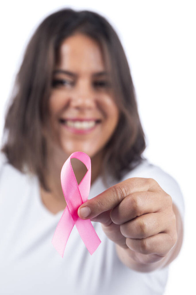 Caucásica chica sosteniendo cáncer de mama cinta sobre un fondo blanco sonriendo. - Foto, imagen