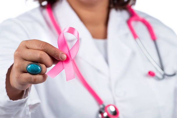 Caucasian doctor woman with pink stethoscope holding breast cancer pink ribbon on a white background. - Foto, imagen