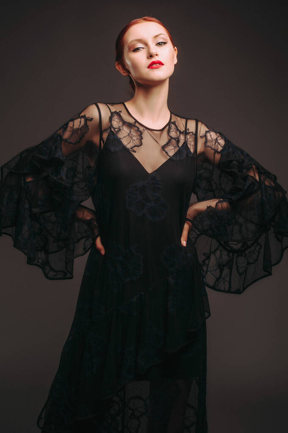 バットスリーブと黒の透明な夜のドレス。ハイヒールを履いた美しいモデル,イベントのための現代的な女性的な外観.女性のファッション。お嬢様. - 写真・画像