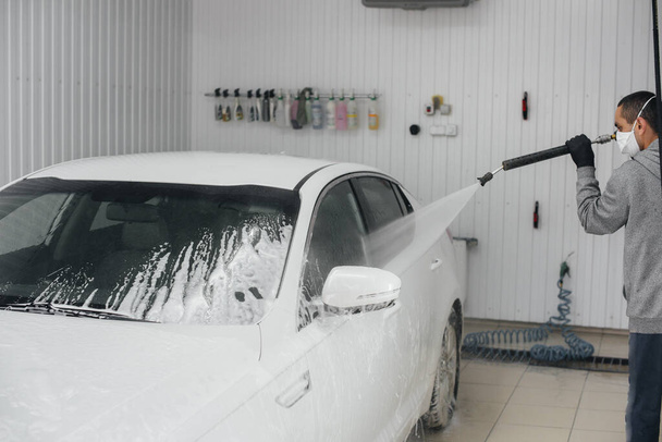 Modern washing with foam and high-pressure water of a white car. Car wash - Foto, Bild