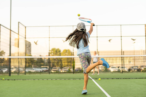 Little girl trying to play tennis on outdoor court - Photo, Image