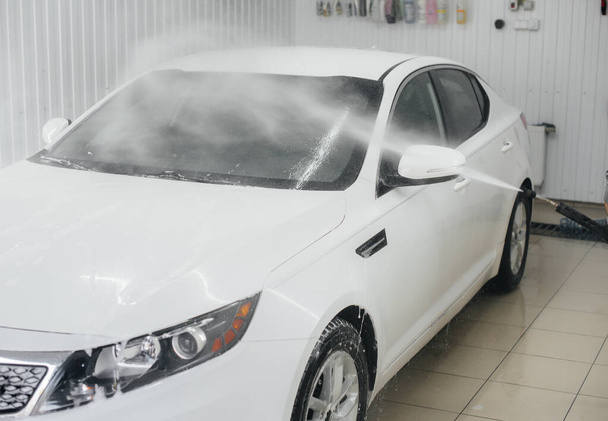 Lavado moderno con espuma y agua de alta presión de un coche blanco. Lavado de coches - Foto, Imagen