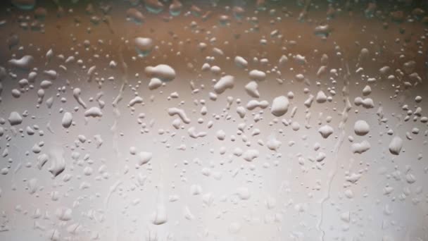 Vista da vicino delle gocce d'acqua che cadono sul vetro. La pioggia sta scendendo dal finestrino. Stagione delle piogge, autunno. Le gocce di pioggia scendono - Filmati, video