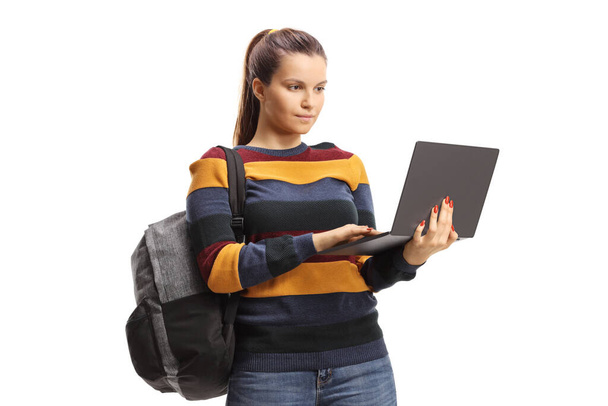 Full length portrait of a female student standing and using a laptop isolated on white background - Valokuva, kuva