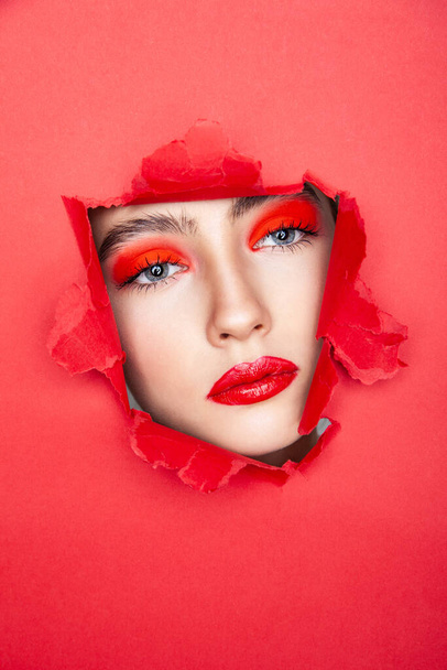 Woman with red visage looking through torn paper - Φωτογραφία, εικόνα