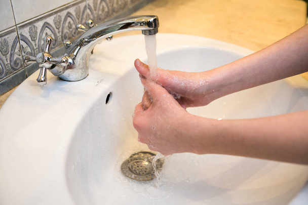Adolescent. Se laver les mains dans le lavabo de la salle de bain. Un lavage fréquent des mains est une condition préalable à une bonne hygiène face à la pandémie de coronavirus. - Photo, image