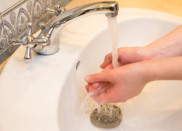 Подросток. Мыть руки в раковине в ванной. Частое мытье рук является необходимым условием хорошей гигиены перед лицом пандемии коронавируса. - Фото, изображение