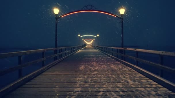 Pari kävelee yöllä puulaiturilla yöllä lumimyrskyssä - Materiaali, video