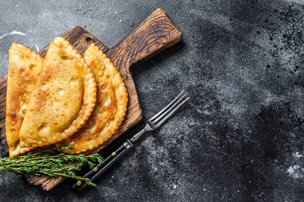 Fried in oil chebureks with meat and herbs, traditional Caucasian cuisine. Black background. Top view. Copy space. - Fotoğraf, Görsel