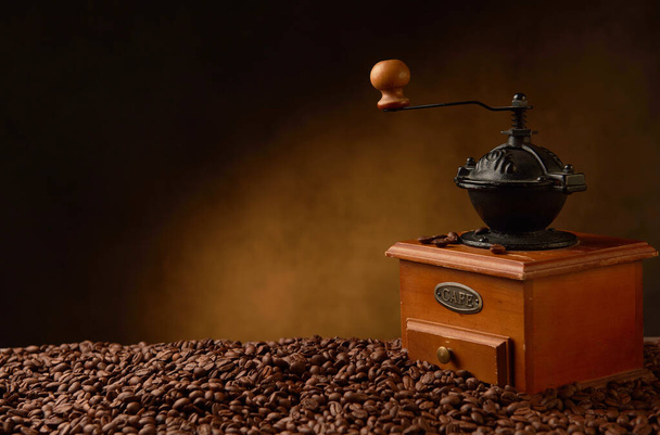 Retro coffee grinder on a table covered with coffee beans - Foto, immagini