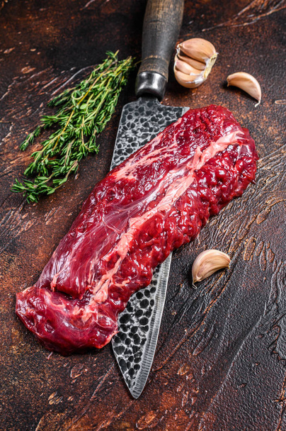 Rauwe biologische machete of rok biefstuk op een slagersmes. Donkere achtergrond. Bovenaanzicht. - Foto, afbeelding
