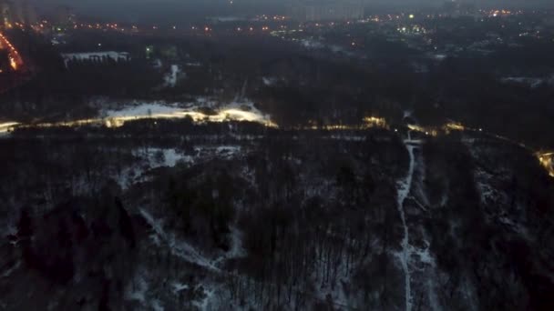 Fly above white wintery evening lights Botanical garden Sarzhyn Yar with cable car on foggy grey winter day. Aerial view in Kharkiv - Footage, Video