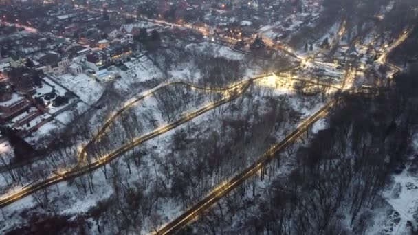 Volar por encima de la noche invernal iluminado Kharkiv parque de la ciudad Jardín botánico con iglesia y parques infantiles en el día de niebla. Vista aérea 4k fondo - Metraje, vídeo