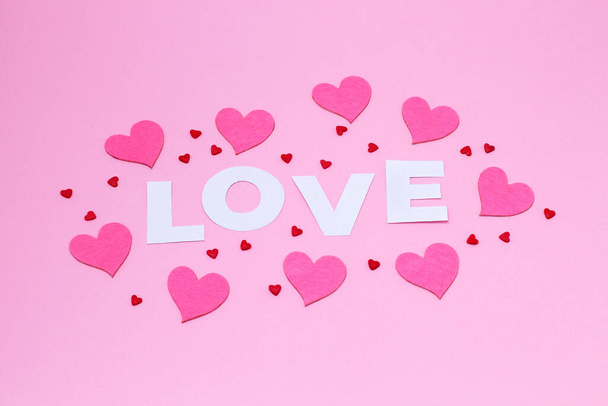 Palabra de amor en letras blancas con fieltro y corazones de azúcar sobre un fondo rosa de moda. Día de San Valentín, Día de la Madre, 8 de marzo, Día Mundial de la Mujer concepto de tarjeta de vacaciones. Puesta plana - Foto, imagen