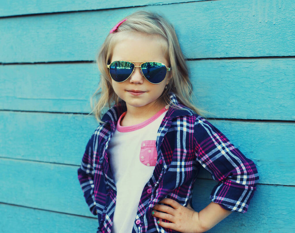 Portrait of stylish little girl child posing on a blue wooden background - Foto, Imagem