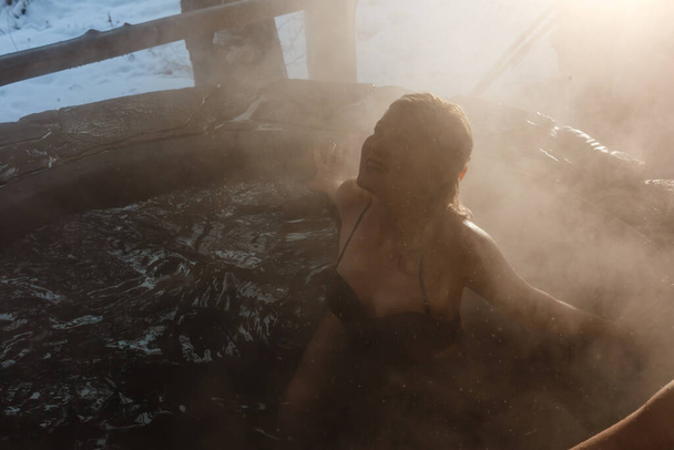 Giovane signora rilassante all'aperto nel bagno termale in inverno - Foto, immagini