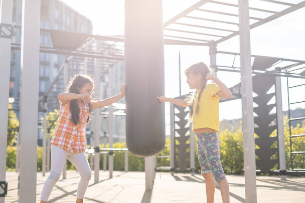 Zwei süße kleine Mädchen amüsieren sich im Sommer auf einem Spielplatz im Freien. Sportliche Aktivitäten für Kinder. - Foto, Bild