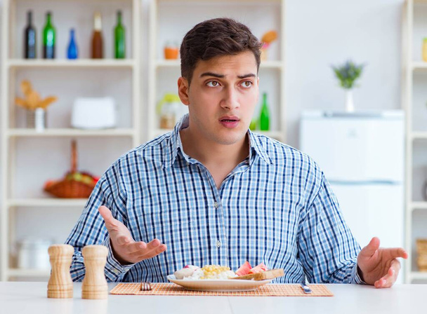 Fiatal férj eszik íztelen étel otthon ebédre - Fotó, kép