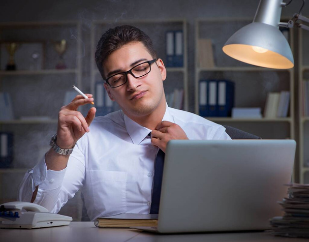 Бизнесмен в состоянии стресса курит в офисе - Фото, изображение