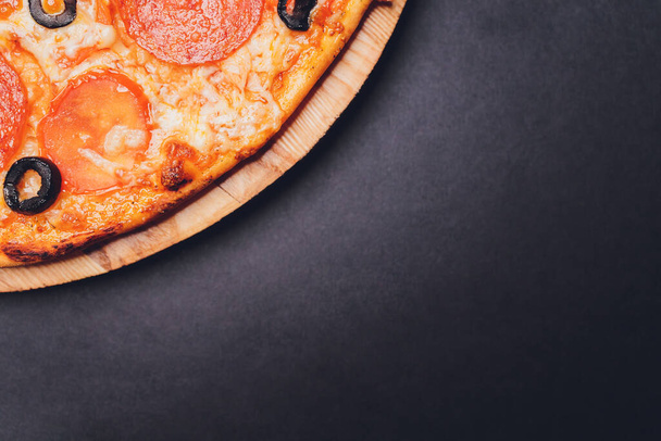 Pizza pepperoni, mozzarella, oregano on a black background. - Foto, afbeelding