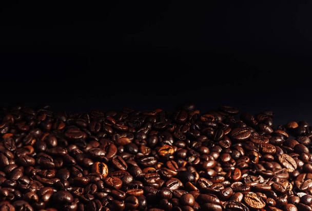 Coffee beans close up. The concept of making aromatic strong coffee on a black background in a low key. Discreet photography. High quality photo - Fotografie, Obrázek